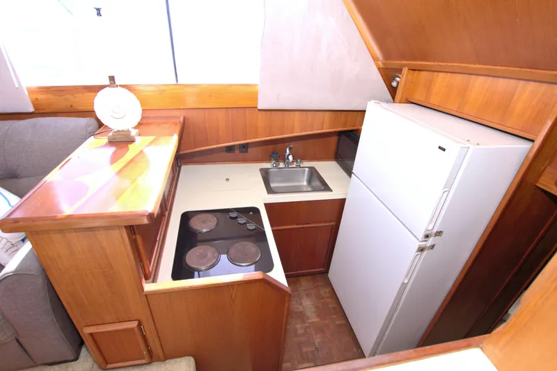 Fishin Post Yacht Photos Pics Compact kitchen in 1990 Post 44 Sport Fisherman boat with stove, sink, and refrigerator.