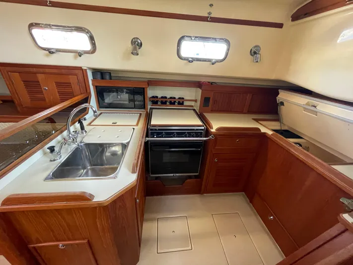  Yacht Photos Pics 2002 Island Packet 380 yacht kitchen with wooden cabinetry and stainless steel sink.