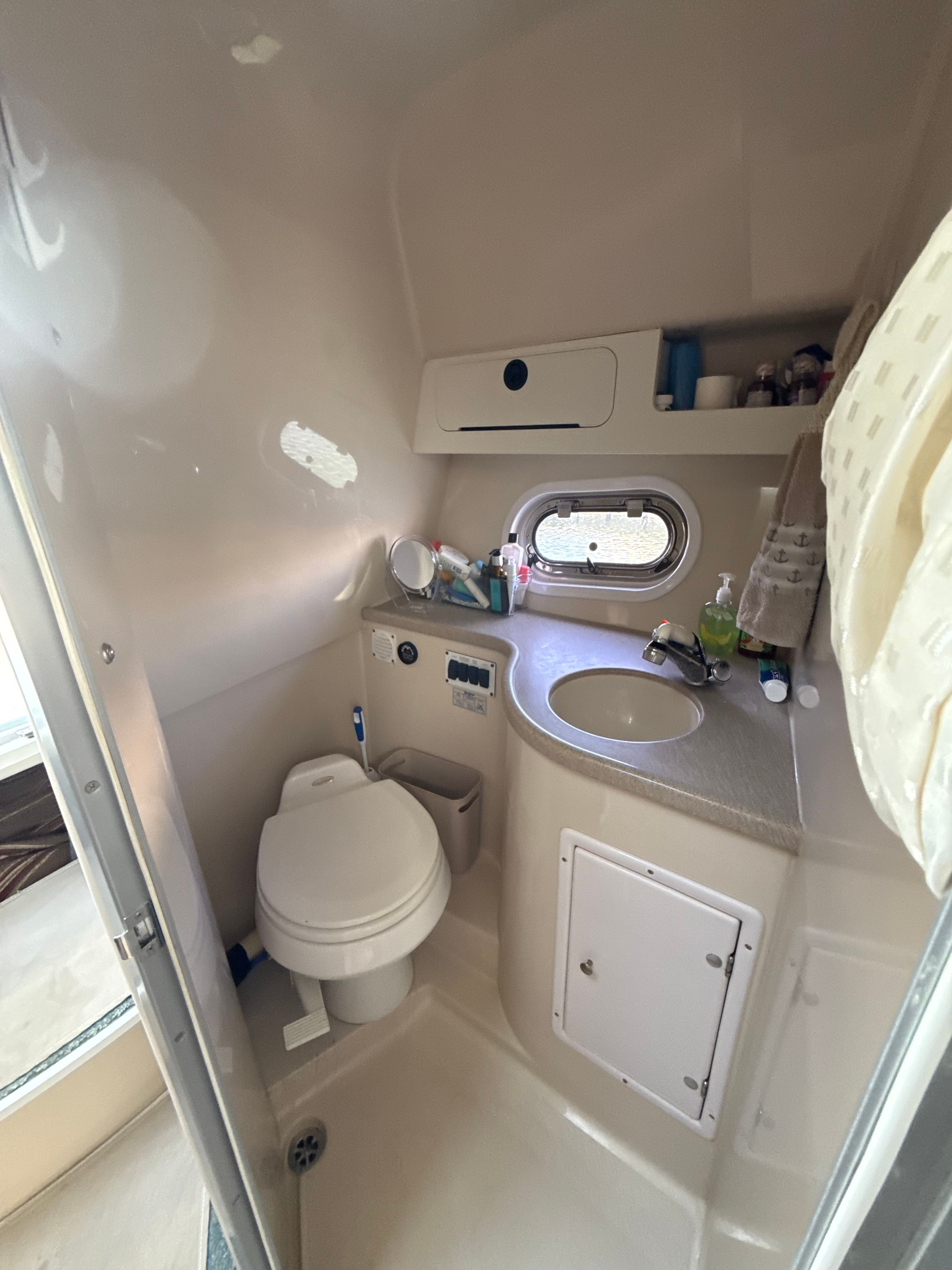 Compact bathroom in a 2004 Four 328 Vista boat, featuring a toilet and sink.