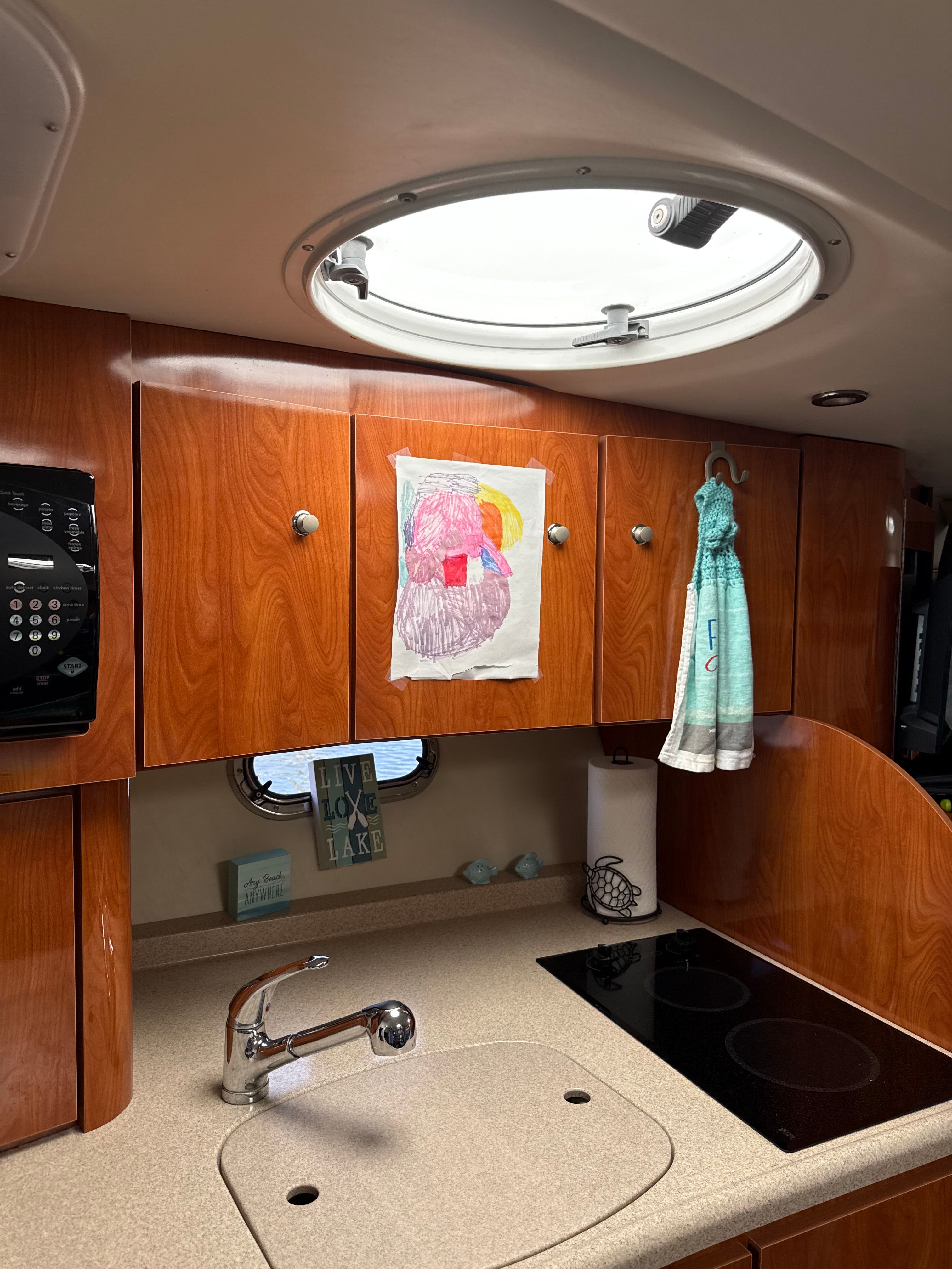 Interior of a 2004 Four 328 Vista boat kitchen with wooden cabinets and a circular skylight.