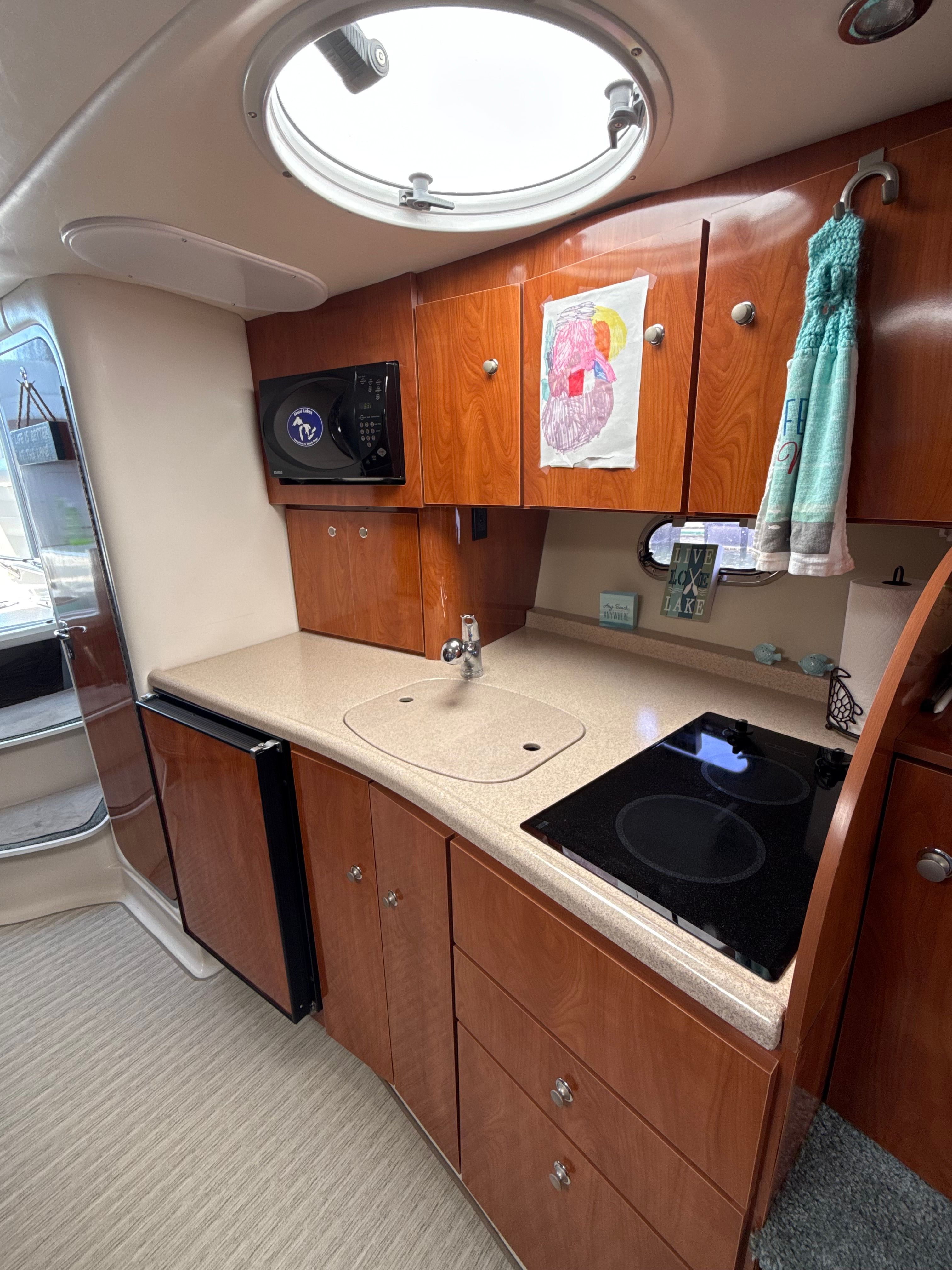 Compact kitchen in 2004 Four 328 Vista boat with wood cabinets and modern appliances.