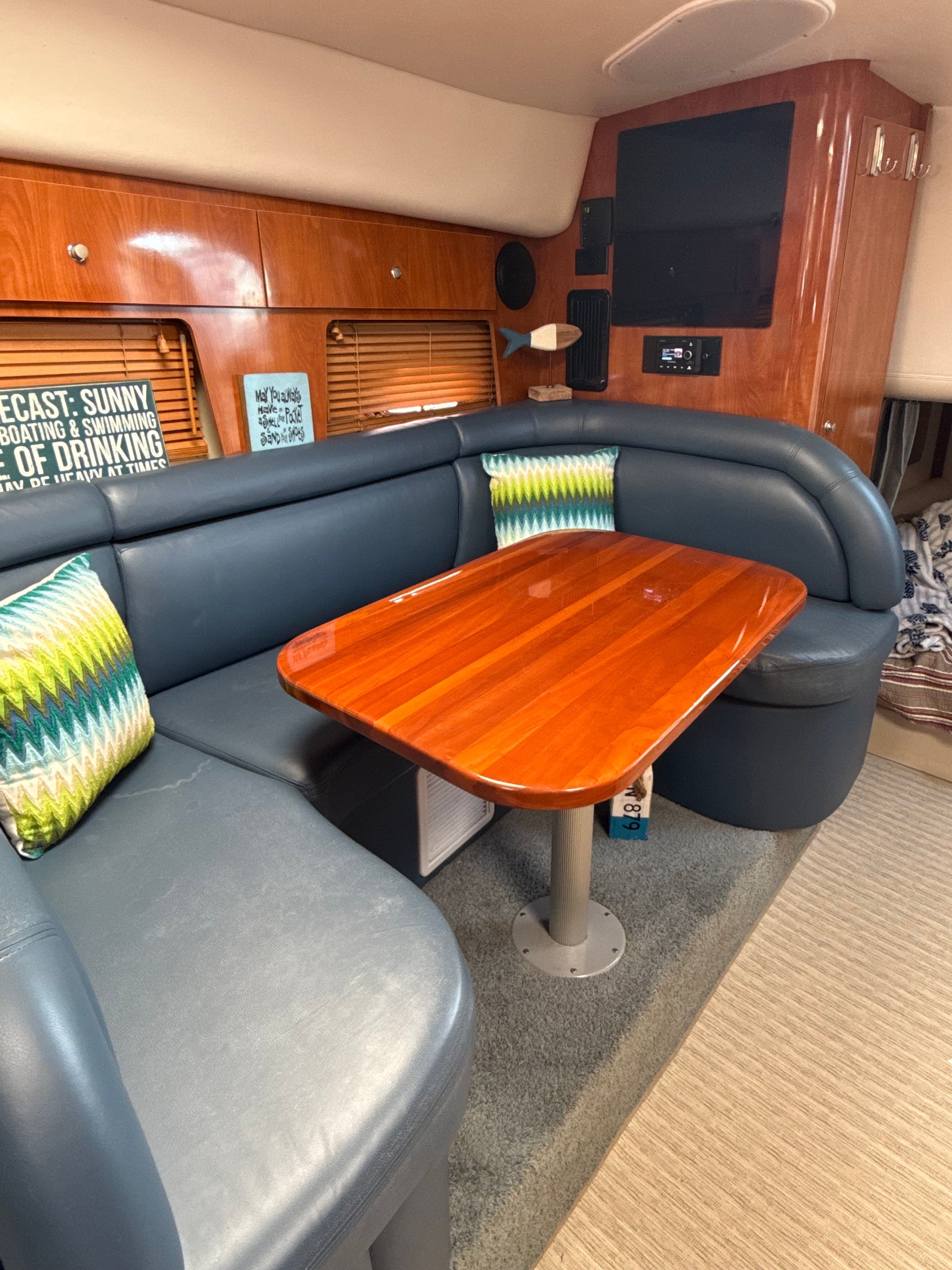 Luxurious 2004 Four 328 Vista yacht interior with wooden table and blue seating.