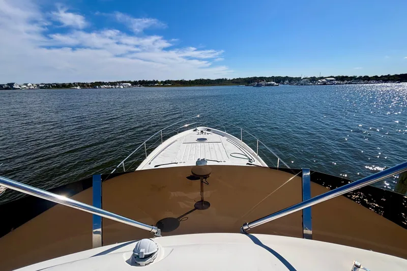  Yacht Photos Pics 2004 Viking Princess 61 Fly Bridge yacht on calm waters under a clear blue sky.