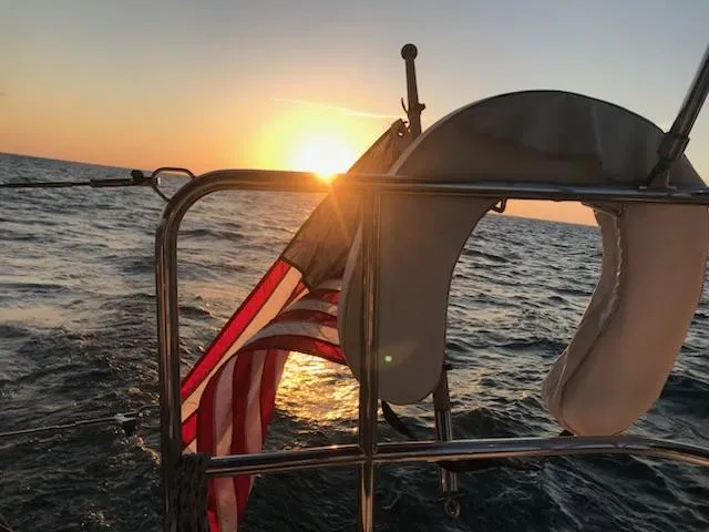  Yacht Photos Pics Jeanneau Sun Odyssey 51 sailing at sunset with American flag, 2017 model.