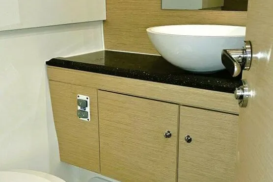  Yacht Photos Pics Modern bathroom interior of 2017 Jeanneau Sun Odyssey 51 yacht with vessel sink and wood cabinetry.