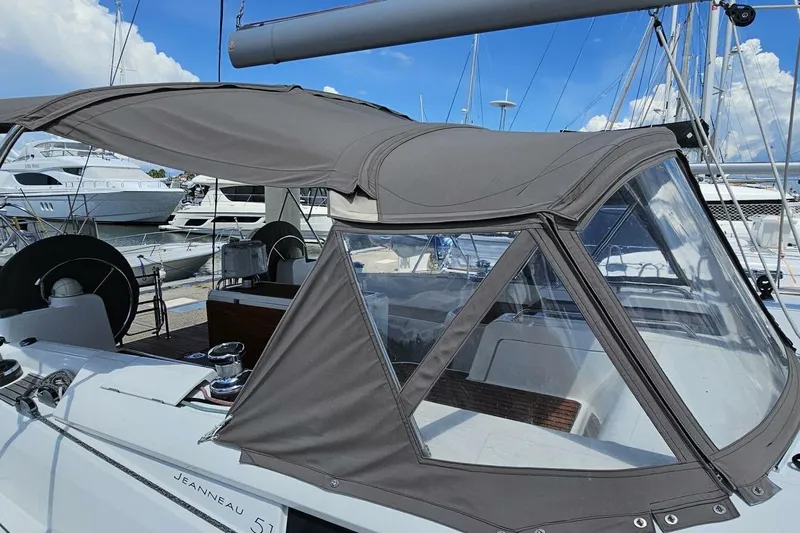  Yacht Photos Pics Jeanneau Sun Odyssey 51 sailboat, 2017 model, with protective canopy in marina setting.