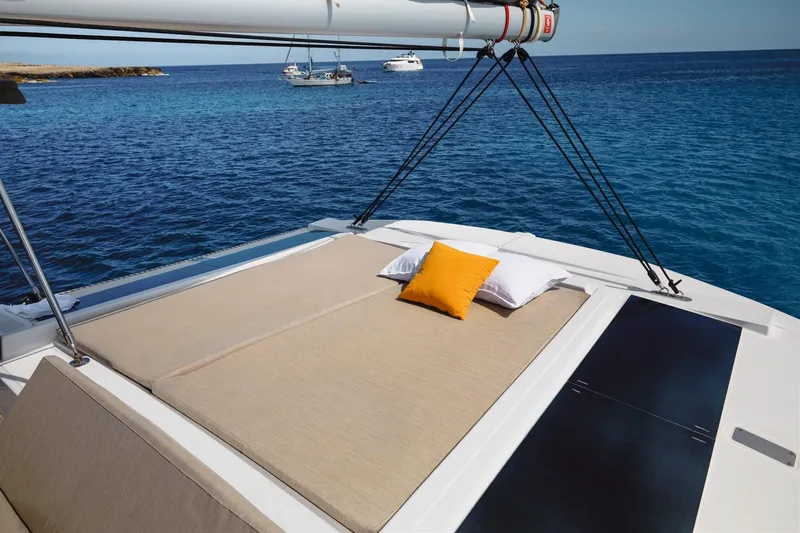 Yulia Yacht Photos Pics Luxurious Bali 4.2 catamaran deck with cushions, anchored in serene blue waters, 2023 model.
