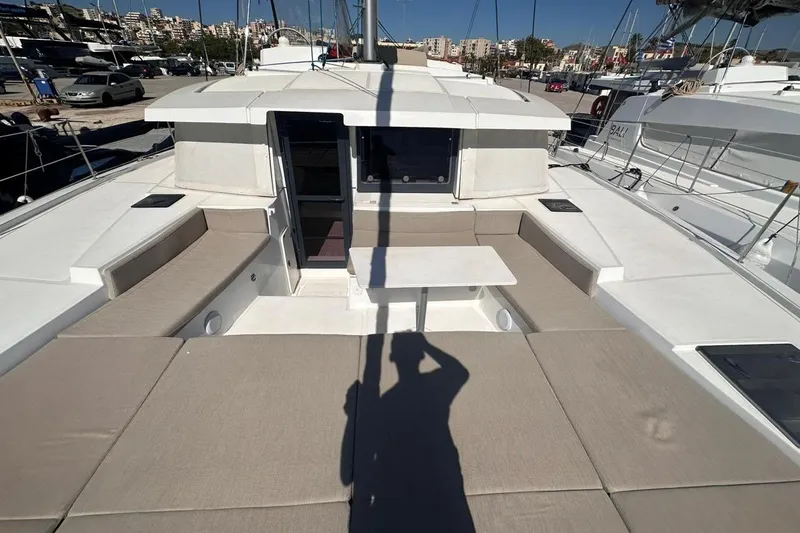 Yulia Yacht Photos Pics 2023 Bali 4.2 yacht deck with seating and table, docked in a marina.