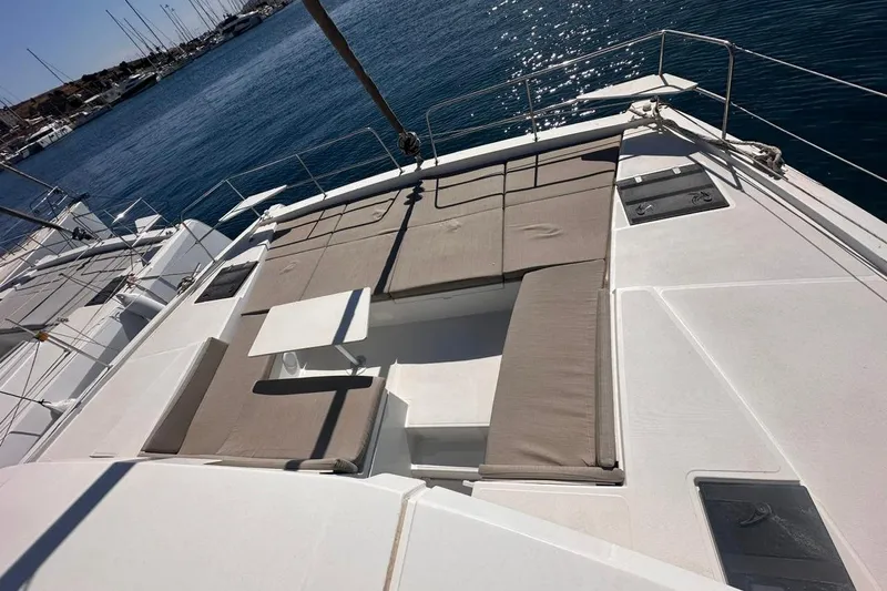 Yulia Yacht Photos Pics 2023 Bali 4.2 yacht deck with cushioned seating and table, docked at marina.
