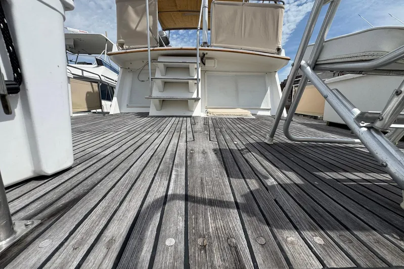 Carolina Breeze Yacht Photos Pics 1989 Grand Banks 42 Motor Yacht deck with wooden flooring and stairs under a blue sky.