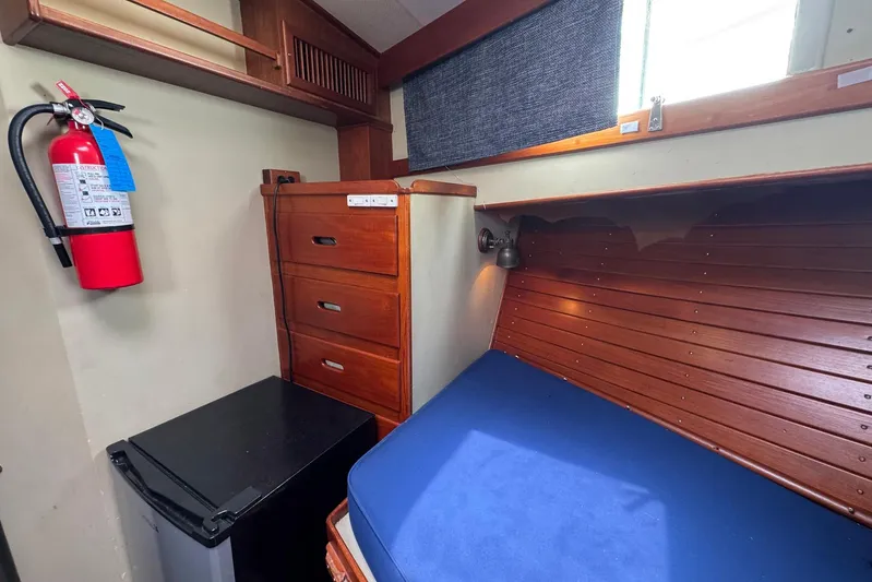 Carolina Breeze Yacht Photos Pics 1989 Grand Banks 42 Motor Yacht cabin with wooden drawers, bed, and fire extinguisher.