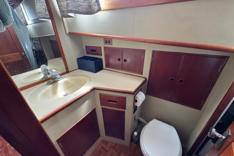 Carolina Breeze Yacht Photos Pics 1989 Grand Banks 42 Motor Yacht bathroom with sink, mirror, and storage cabinets.