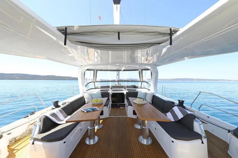 Volare Yacht Photos Pics Luxurious 2025 Hanse 590 yacht interior with elegant seating and tables, overlooking serene blue waters.