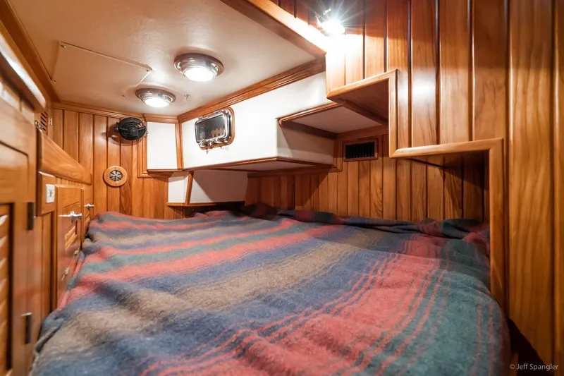 Skoal Yacht Photos Pics Cozy cabin interior of 2005 Cabo Rico 42 Pilot with wood paneling and striped bedding.
