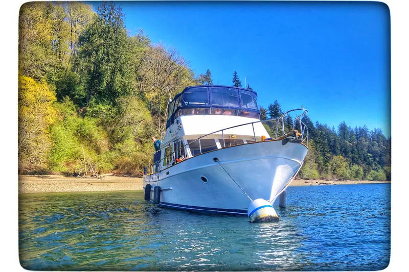 Positive Space Yacht Photos Pics 1987 DeFever Trawler anchored in scenic, forested waters under a clear blue sky.