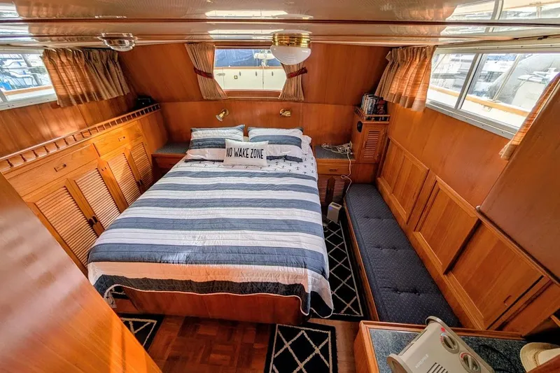 Positive Space Yacht Photos Pics 1987 DeFever Trawler cabin with striped bedding, wood paneling, and "No Wake Zone" pillow.