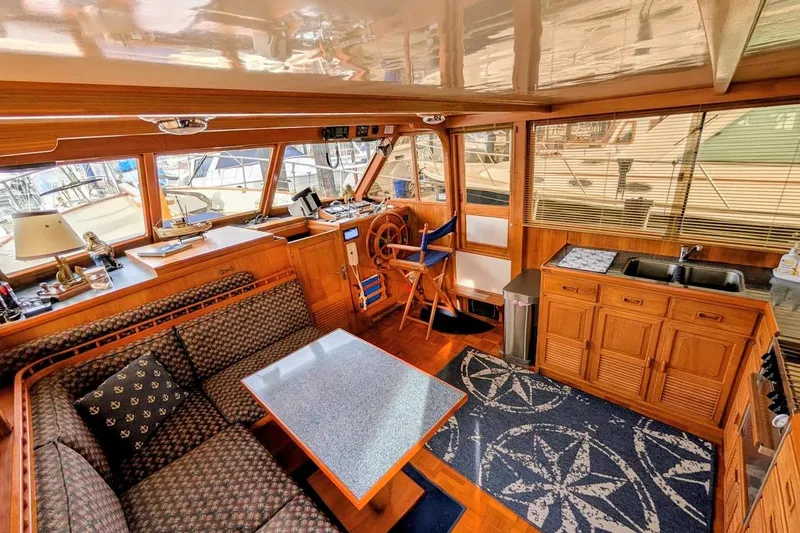 Positive Space Yacht Photos Pics 1987 DeFever Trawler interior with wooden decor, seating area, helm, and kitchenette.