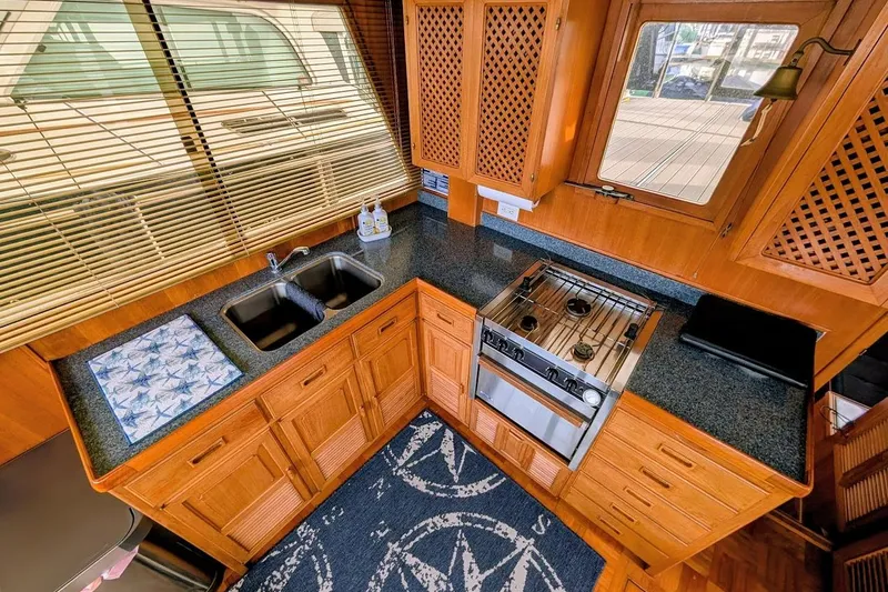 Positive Space Yacht Photos Pics 1987 DeFever Trawler kitchen with wooden cabinets, dual sink, stove, and nautical-themed decor.