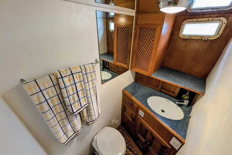 Positive Space Yacht Photos Pics 1987 DeFever Trawler bathroom with wooden cabinets, sink, and checkered towels.