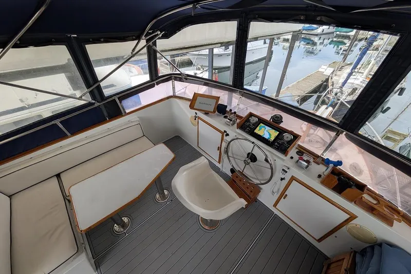 Positive Space Yacht Photos Pics 1987 DeFever Trawler helm with navigation equipment, seating, and marina view.