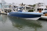 2018 Mystic Powerboats M4200 in marina, sleek blue design, docked near waterfront homes.