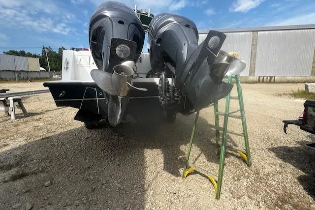  Yacht Photos Pics 1999 Contender 27 Open Center Console with dual outboard motors on a gravel lot.
