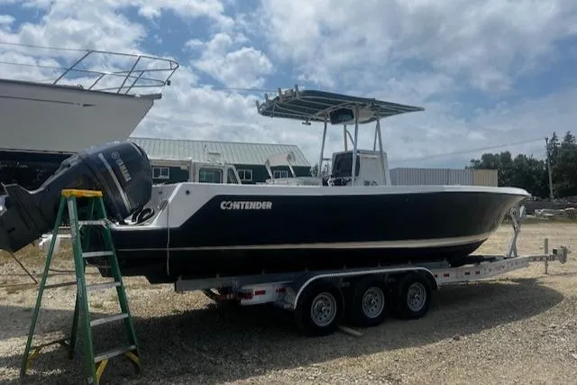 Yacht Photos Pics 1999 Contender 27 Open Center Console boat on trailer, parked outdoors under cloudy sky.