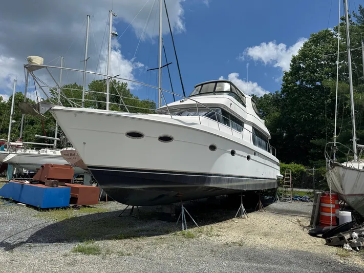 Beautiful Crazy Yacht Photos Pics 2003 Carver 570 Voyager Pilothouse yacht on dry dock, surrounded by trees and other boats.