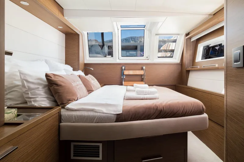 Duolife Yacht Photos Pics Luxurious cabin interior of 2019 Lagoon 620 Essence yacht with modern wood finishes and cozy bedding.