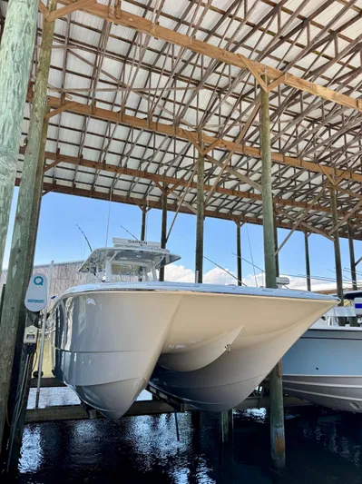  Yacht Photos Pics 2022 Invincible 46 Catamaran docked under a wooden shelter.