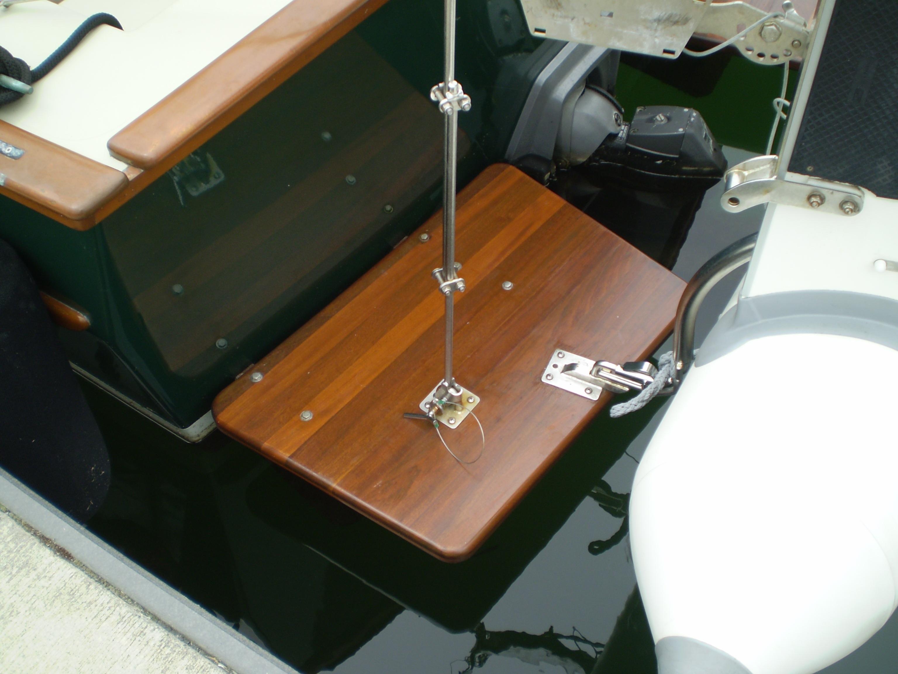 Devlin Surf Scoter 2000 boat with wooden swim platform and motor, docked on calm water.
