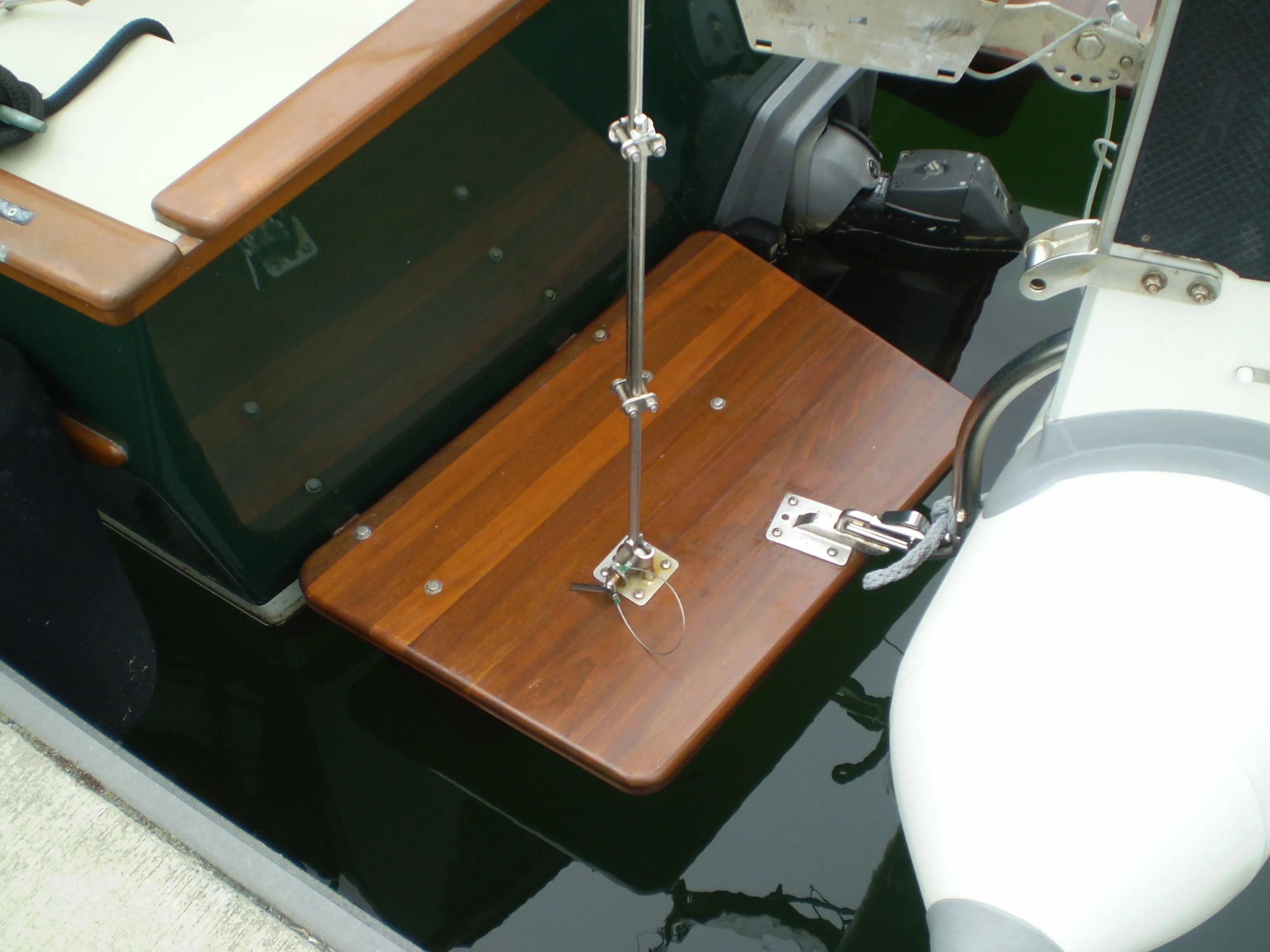 Devlin Surf Scoter 2000 boat with wooden swim platform and motor, docked on calm water.