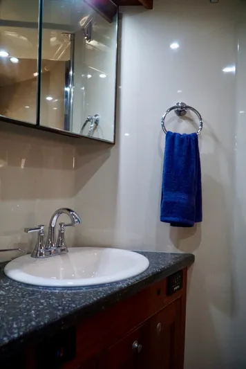 Kaizen Yacht Photos Pics Bathroom sink area in 2007 Cruisers Yachts 560 Express with blue towel and mirrored cabinet.