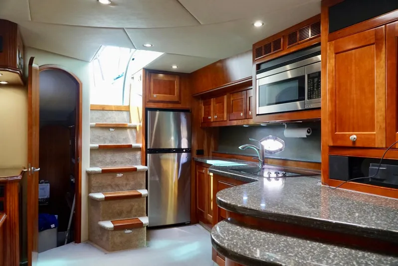 Kaizen Yacht Photos Pics 2007 Cruisers Yachts 560 Express kitchen with stainless steel appliances and wooden cabinetry.