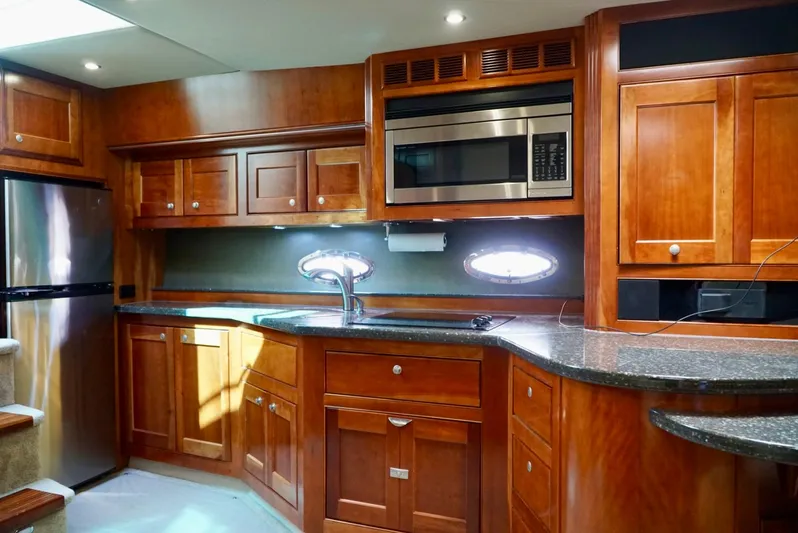 Kaizen Yacht Photos Pics 2007 Cruisers Yachts 560 Express kitchen with wooden cabinetry and modern appliances.