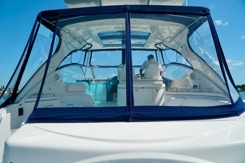 Kaizen Yacht Photos Pics 2007 Cruisers Yachts 560 Express cockpit with blue canopy and captain at helm.