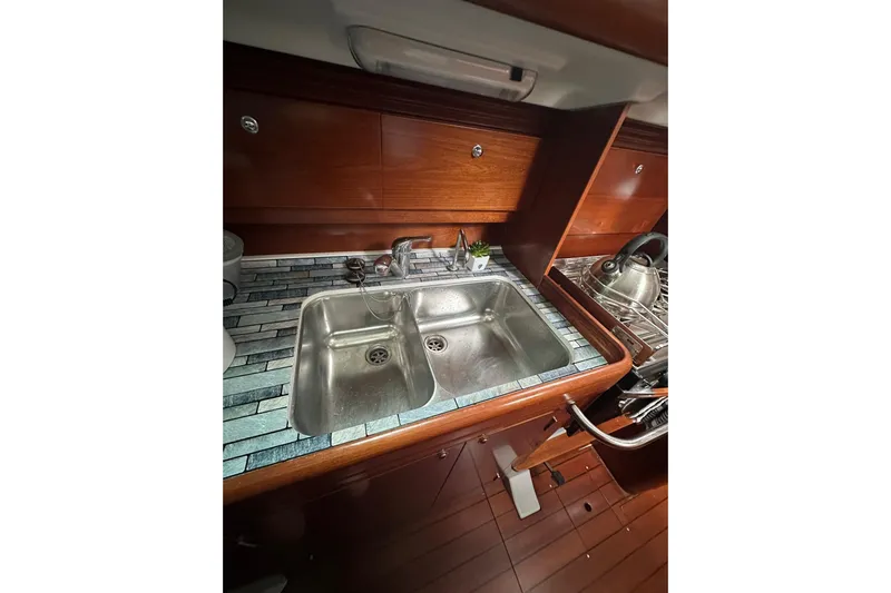 Gemini's Escape II Yacht Photos Pics Galley sink in 2005 Beneteau Oceanis 42CC yacht with wooden cabinetry and tiled countertop.