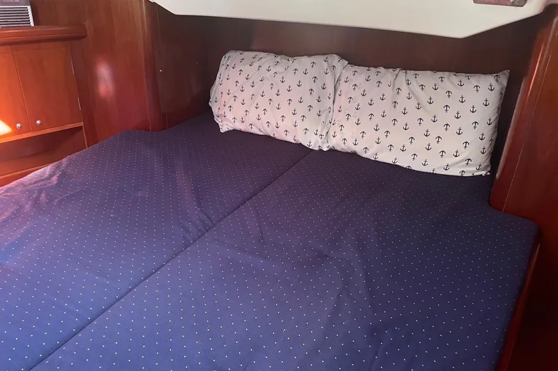 Gemini's Escape II Yacht Photos Pics Cozy cabin bed in 2005 Beneteau Oceanis 42CC yacht with nautical-themed pillows.