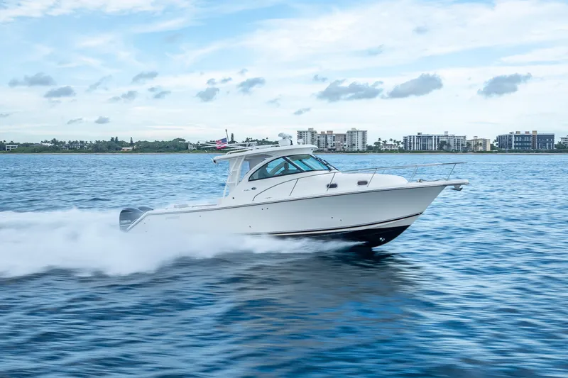 "seven C's" Yacht Photos Pics 2011 Pursuit OS 345 Offshore boat cruising on open water, cityscape in background.