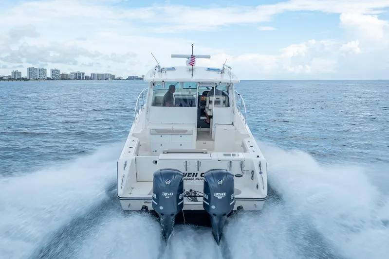 "seven C's" Yacht Photos Pics 2011 Pursuit OS 345 Offshore boat cruising on open water with city skyline in background.
