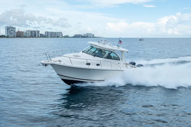 "seven C's" Yacht Photos Pics 2011 Pursuit OS 345 Offshore boat cruising on open water near city skyline.
