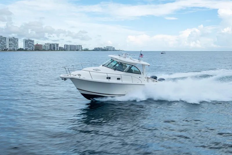 "seven C's" Yacht Photos Pics 2011 Pursuit OS 345 Offshore boat cruising on open water with city skyline backdrop.