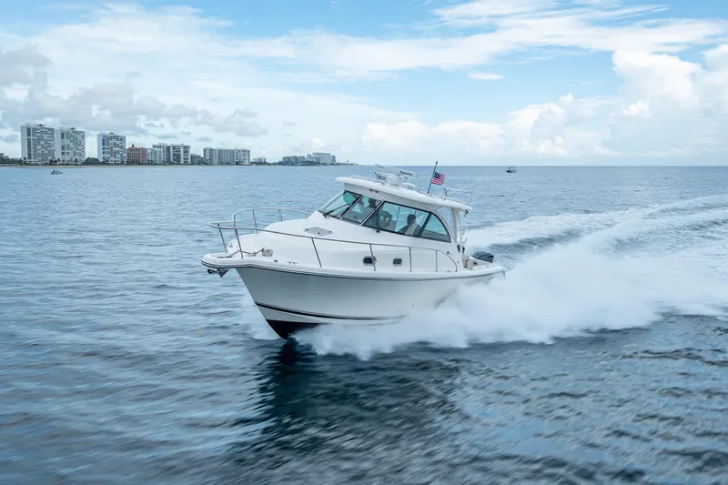 "seven C's" Yacht Photos Pics 2011 Pursuit OS 345 Offshore boat cruising on open water near city skyline.