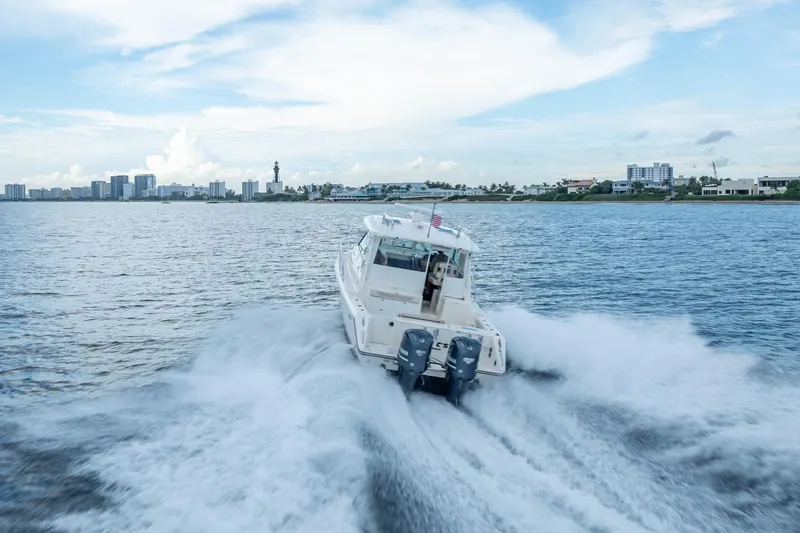 "seven C's" Yacht Photos Pics 2011 Pursuit OS 345 Offshore boat cruising on open water with city skyline backdrop.