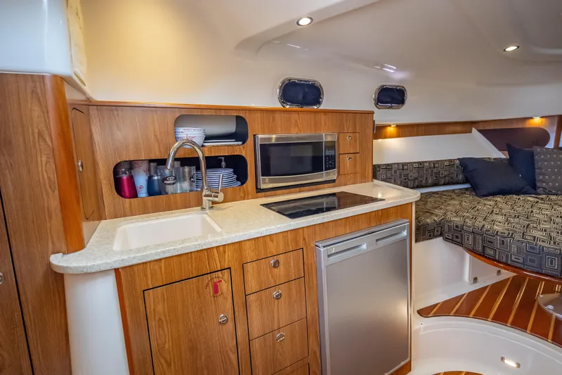 "seven C's" Yacht Photos Pics 2011 Pursuit OS 345 Offshore boat interior with kitchenette, sink, microwave, and cozy seating area.