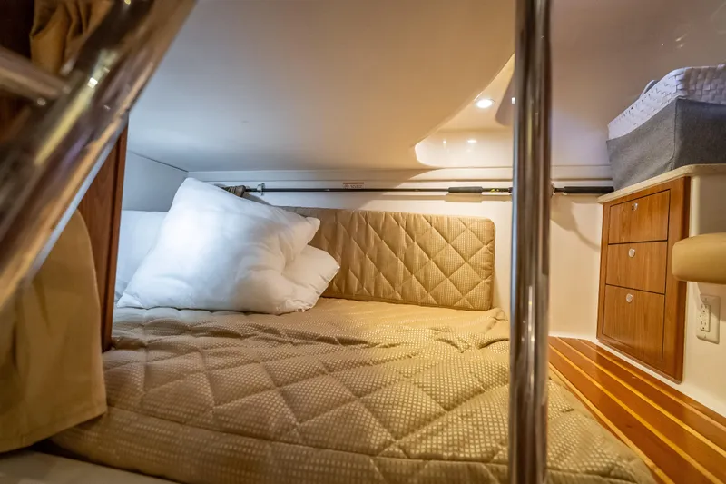 "seven C's" Yacht Photos Pics Cozy cabin interior of 2011 Pursuit OS 345 Offshore boat with bed and wooden drawers.
