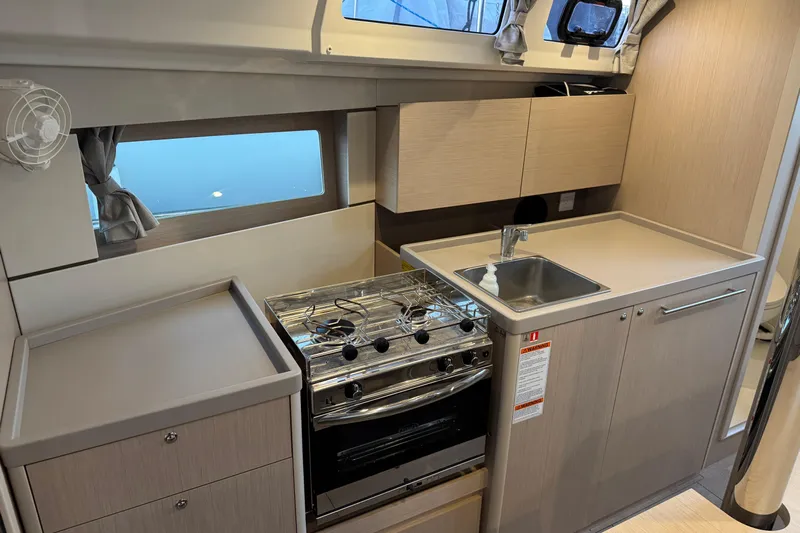 Barcelona Yacht Photos Pics Modern kitchen in 2021 Beneteau Oceanis 35.1 yacht with stove, sink, and storage cabinets.