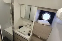 Modern bathroom in 2023 Cranchi F 52 yacht with shower, sink, and porthole window.
