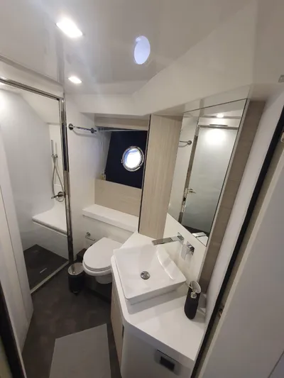 Avalon Yacht Photos Pics Modern bathroom in 2023 Cranchi F 52 yacht, featuring sleek fixtures and a porthole window.