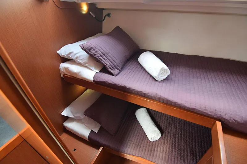  Yacht Photos Pics Bunk beds in 2015 Beneteau Oceanis 48 yacht cabin with purple bedding and rolled towels.